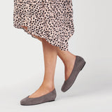 dark grey flat shoes worn by a woman in a dotty dress