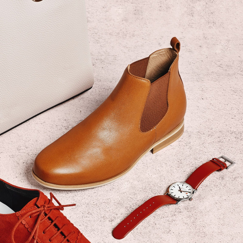 tan leather flat boot next to a red watch